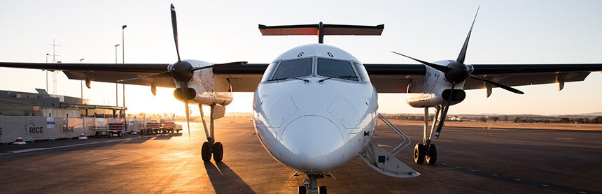 A small aircraft on the runway with the sun setting behind it