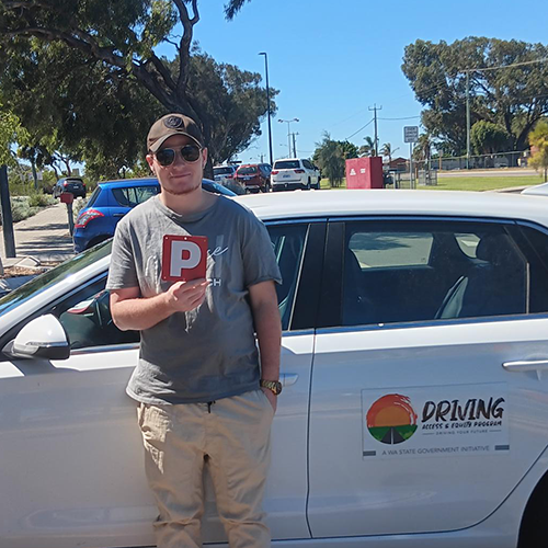 Stuart holding his P plates, after being assisted on his licensing journey by PCYC