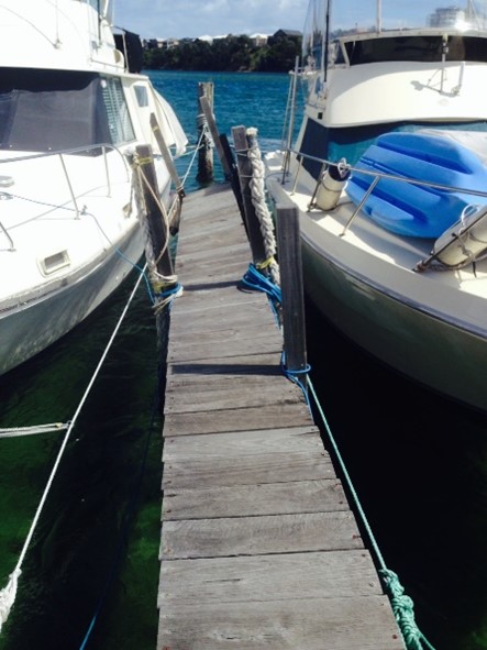 damaged harbour infrastructure with boats either side of walkway